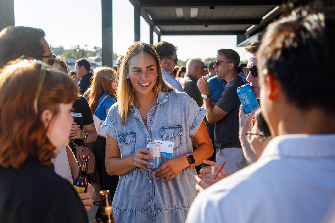 young woman smiles while talking to peers at networking event
