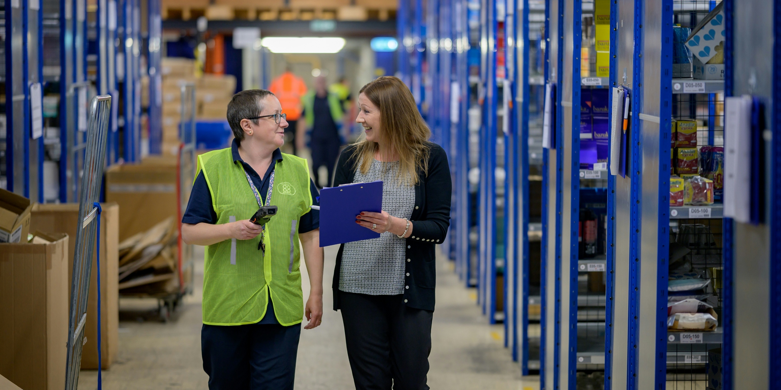 two employees walk through a warehouse taking inventory