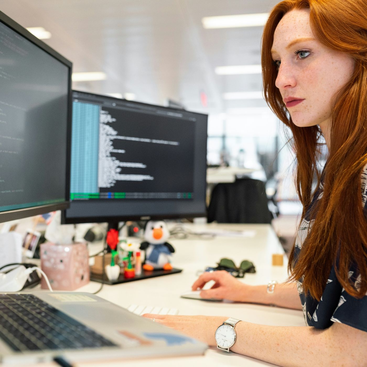 female developer works on multiple computer screens